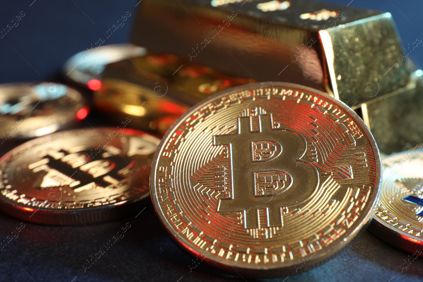 Photo of Bitcoins and gold bars on blue background, closeup