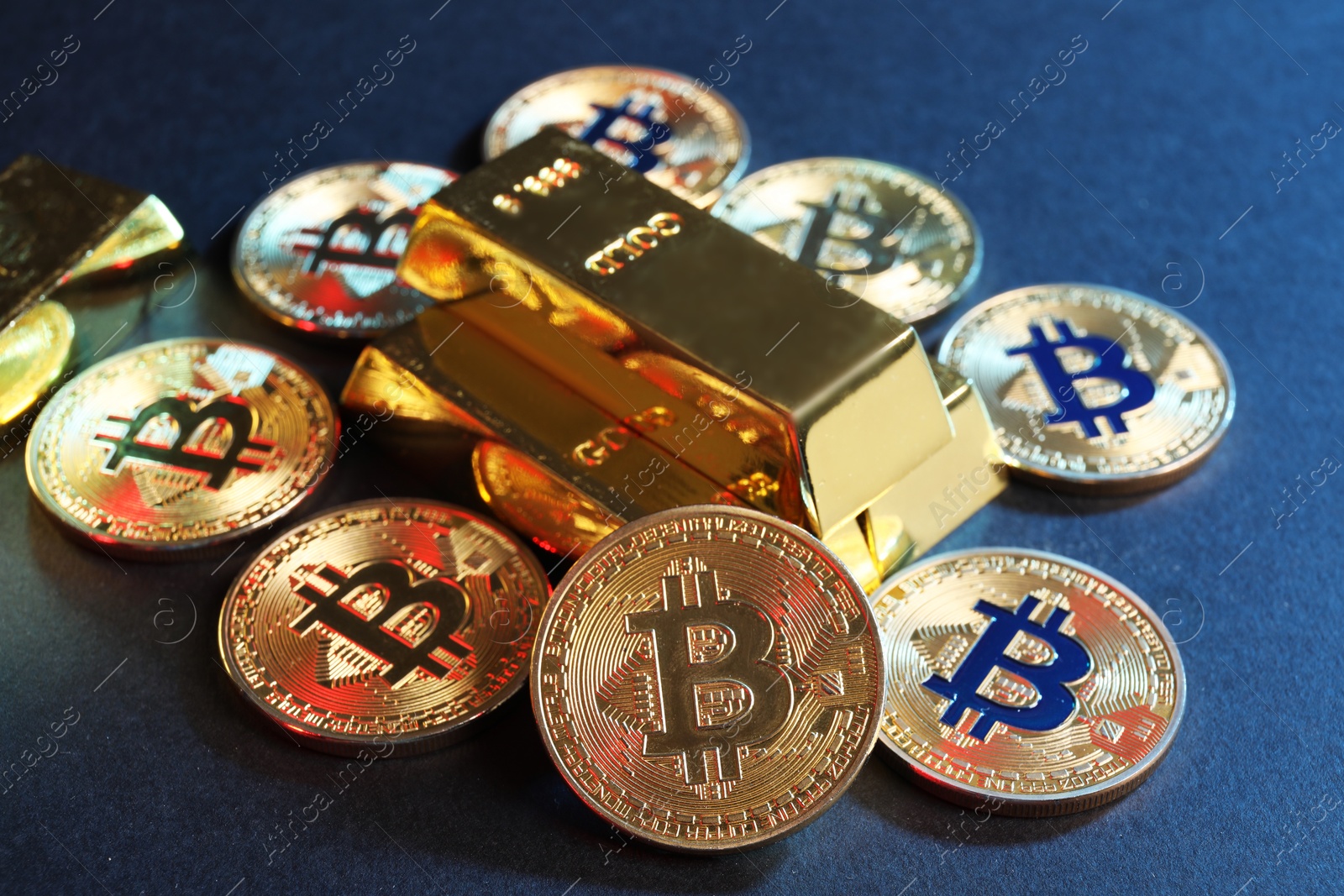 Photo of Bitcoins and gold bars on blue background, closeup