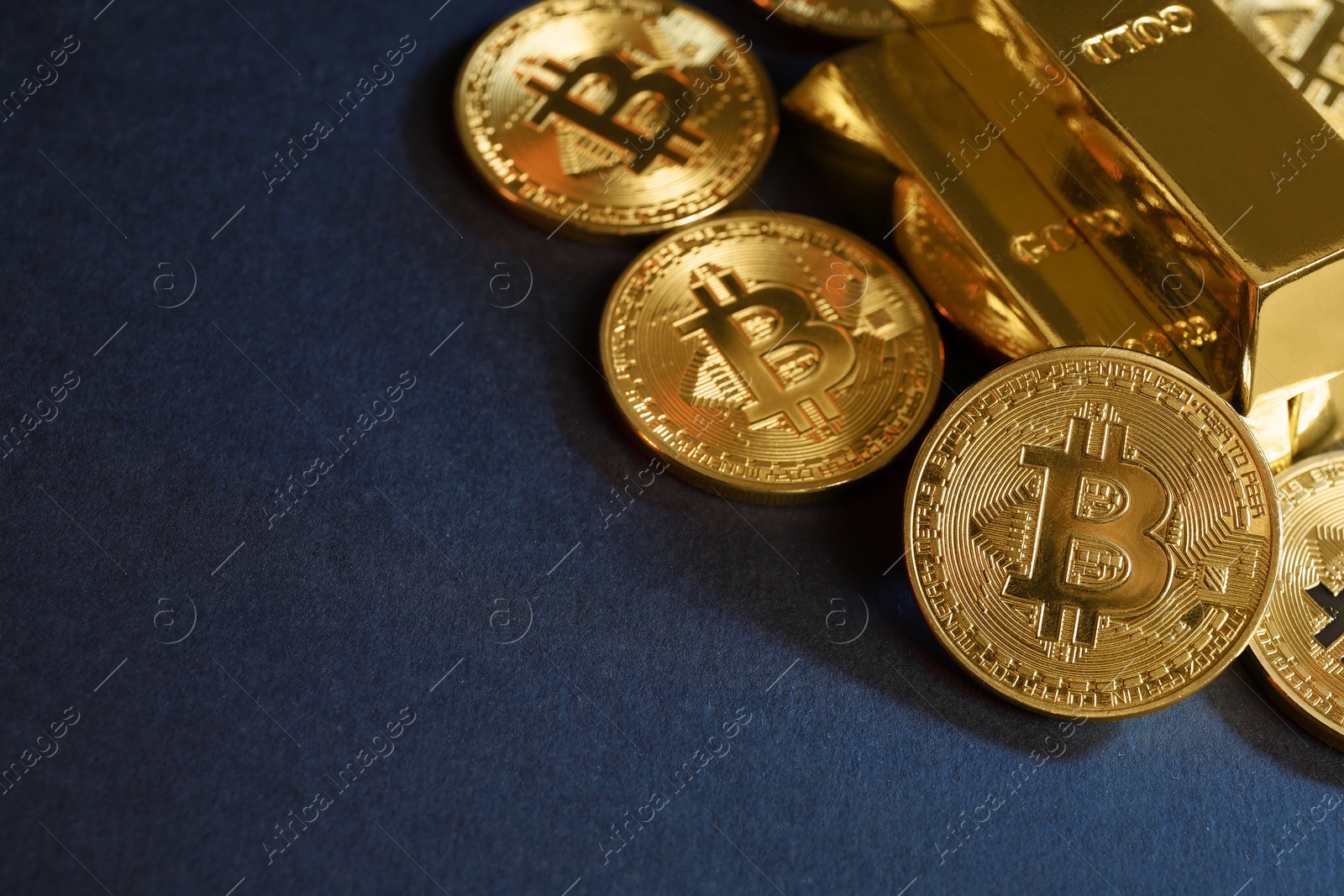 Photo of Bitcoins and gold bars on blue background, closeup. Space for text