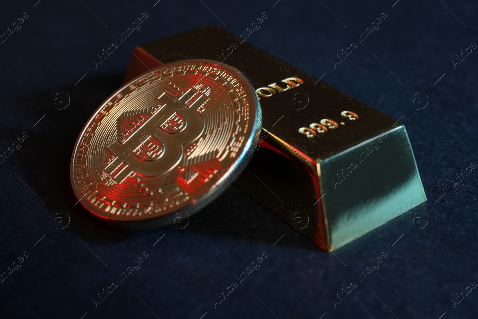 Photo of Bitcoin and gold bar on blue background, closeup