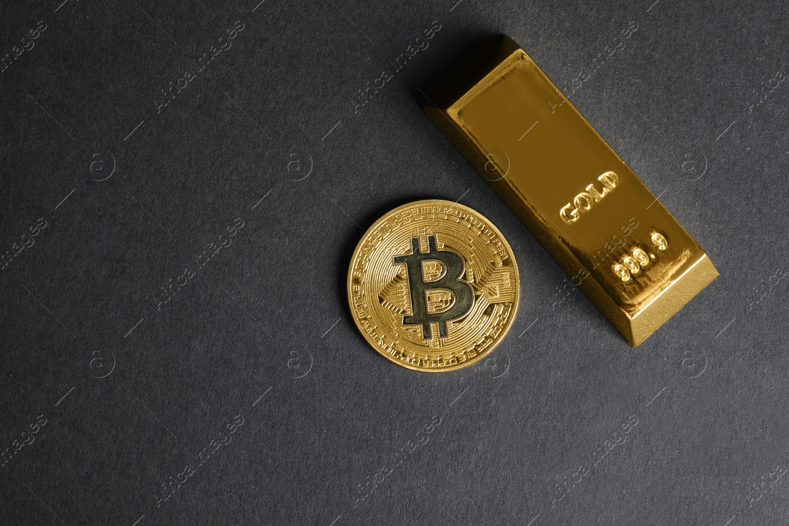 Photo of Bitcoin and gold bar on black background, top view