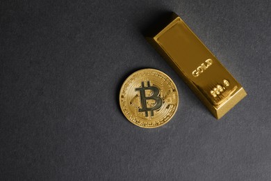 Photo of Bitcoin and gold bar on black background, top view