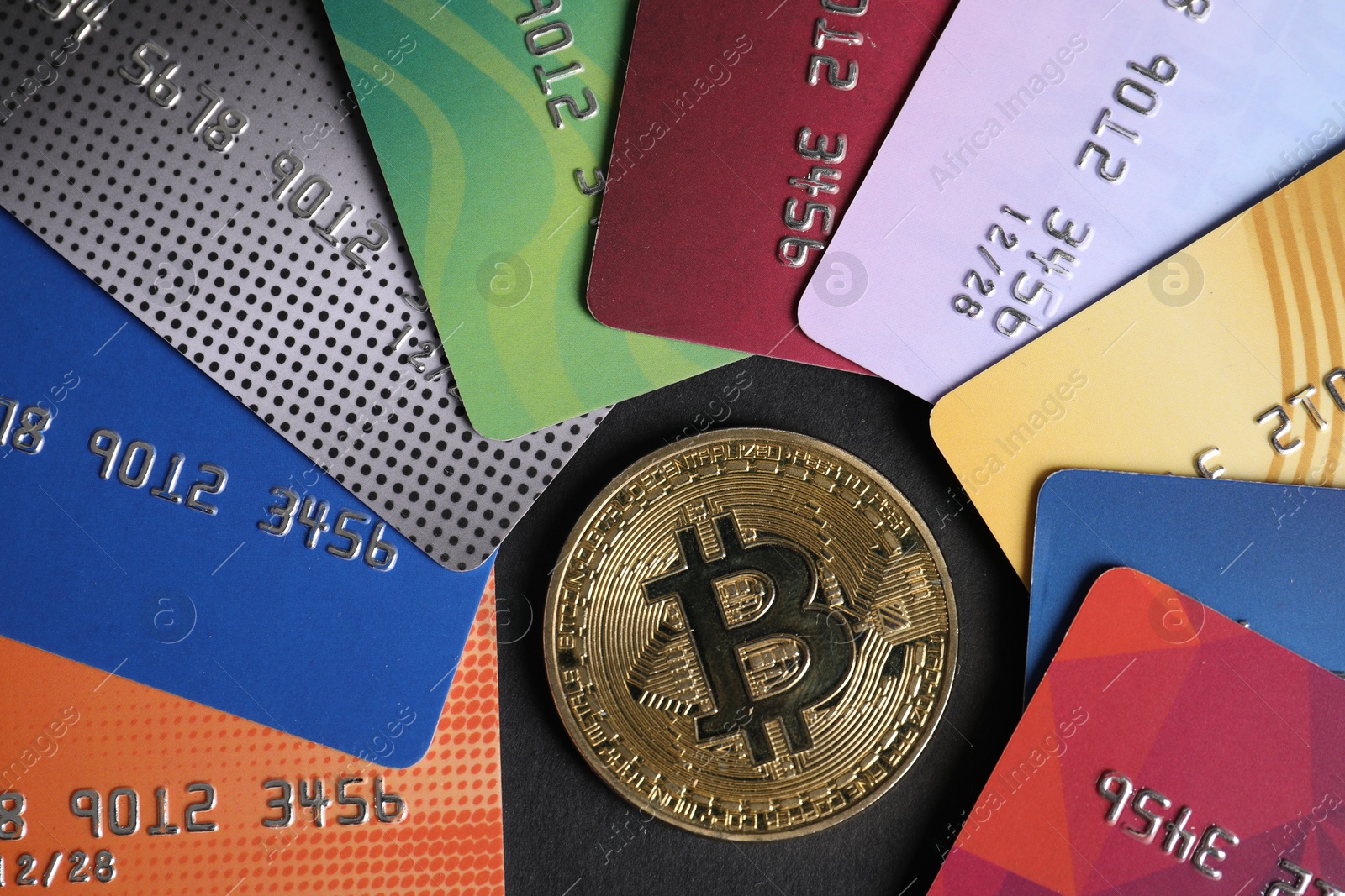Photo of Bitcoin and plastic bank cards on black background, flat lay