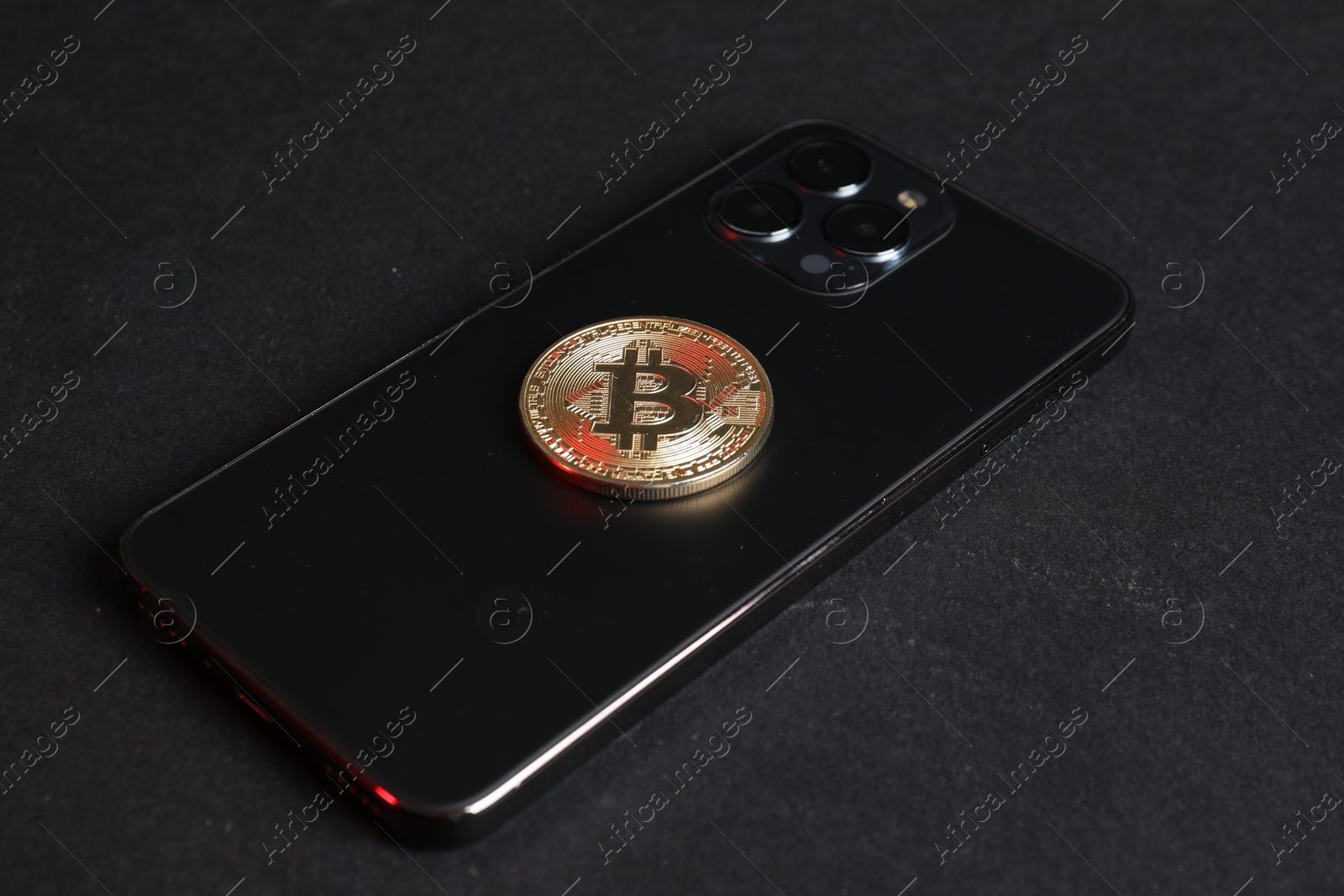 Photo of Smartphone with bitcoin on black background, closeup