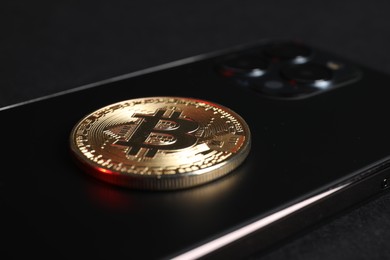 Photo of Smartphone with bitcoin on black background, closeup