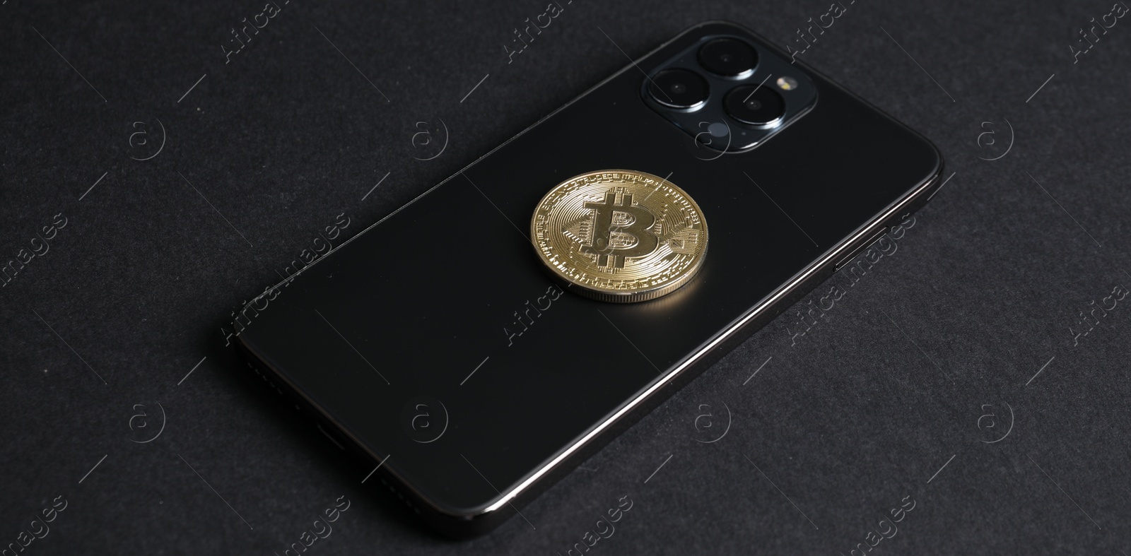 Photo of Smartphone with bitcoin on black background, closeup