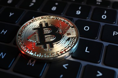 Photo of Cryptocurrency. Bitcoin on laptop keyboard, closeup view