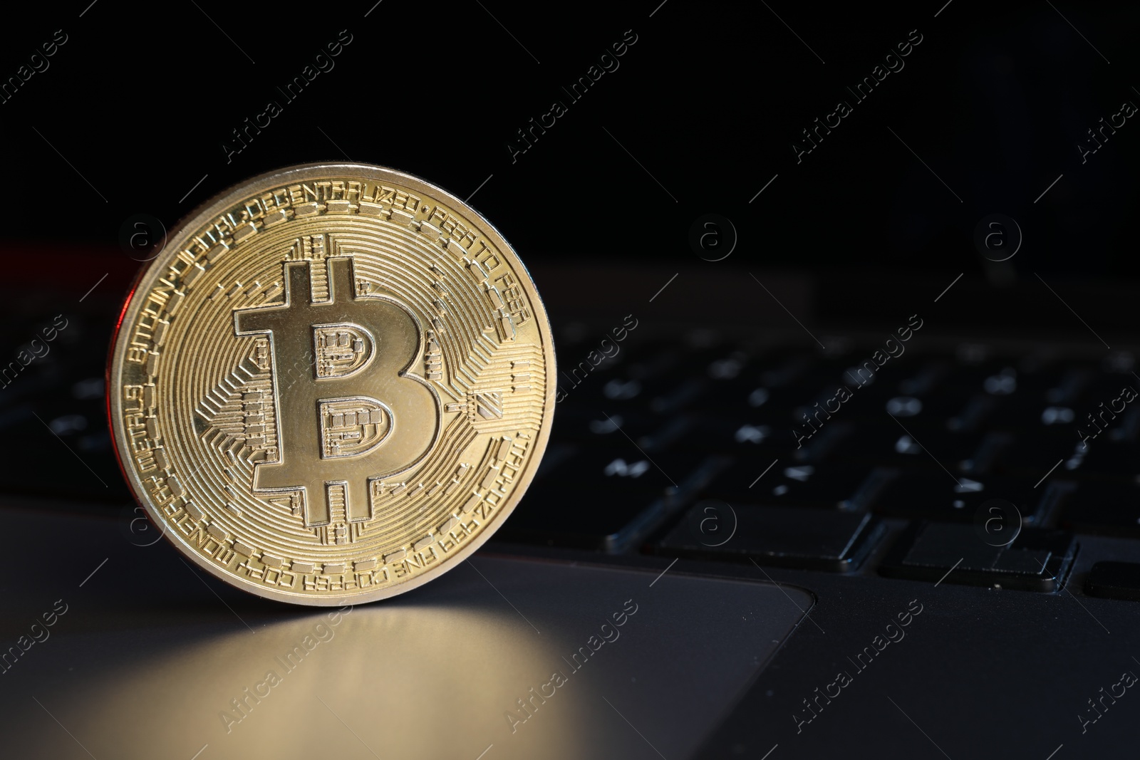 Photo of Cryptocurrency. Golden bitcoin on laptop, closeup view