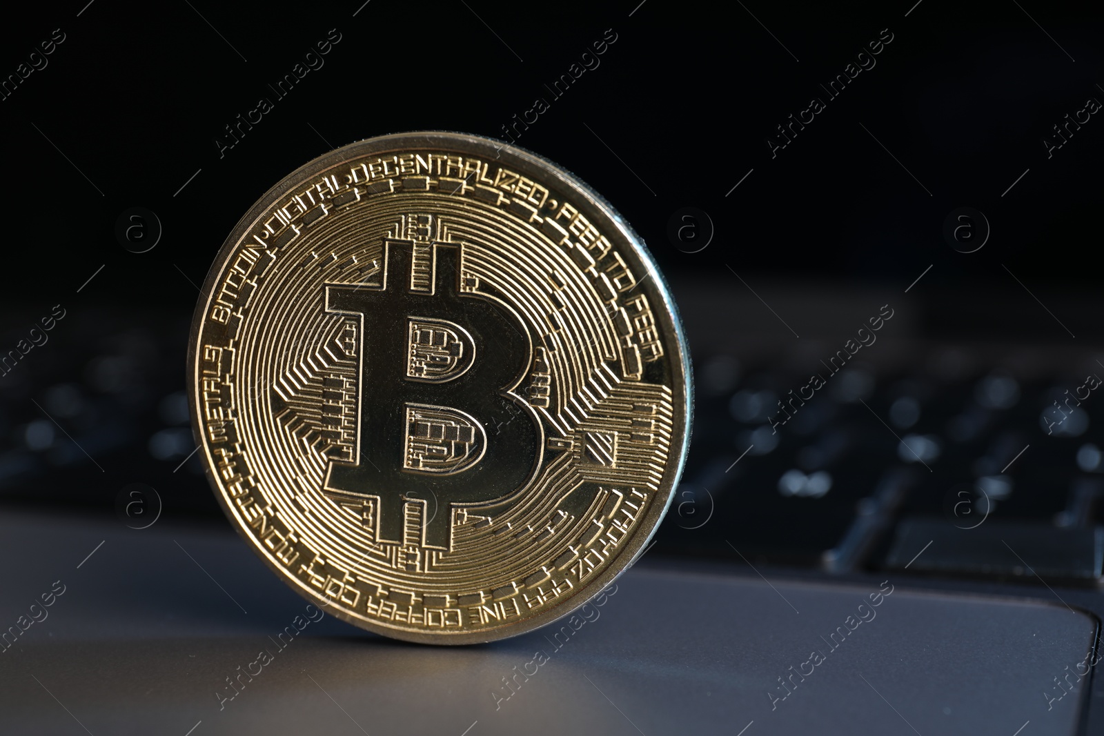 Photo of Cryptocurrency. Golden bitcoin on laptop, closeup view