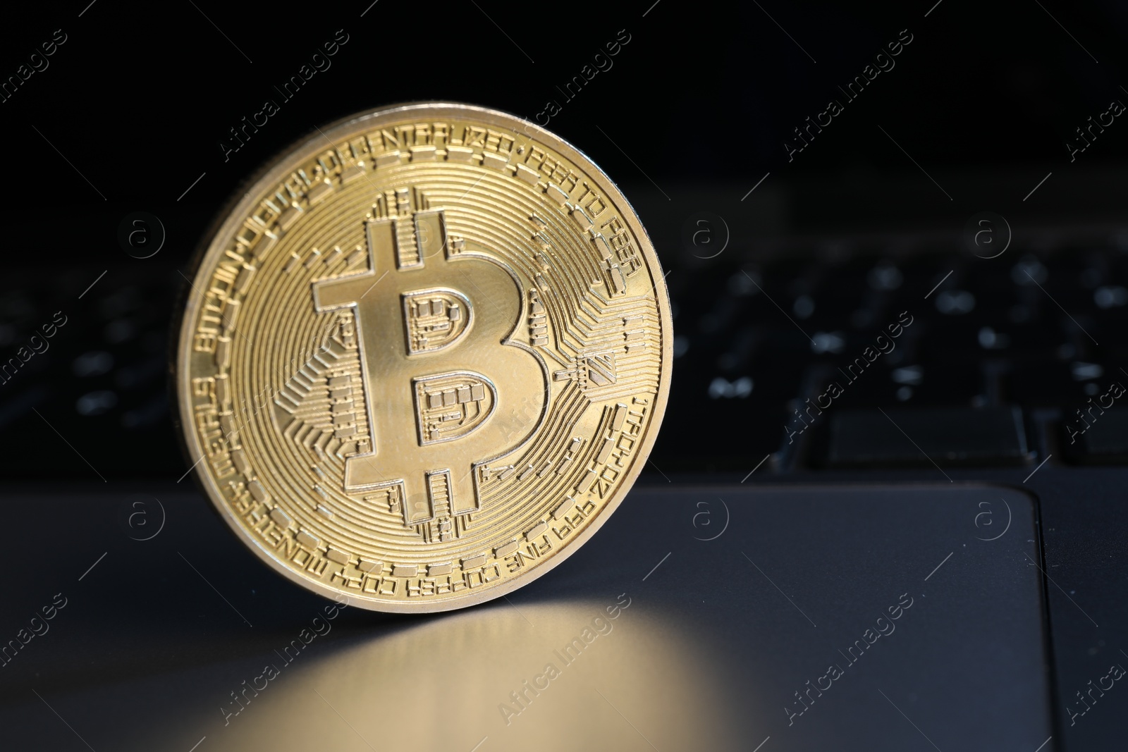 Photo of Cryptocurrency. Golden bitcoin on laptop, closeup view