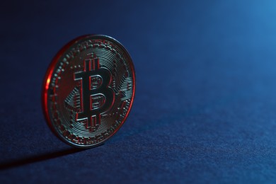 Photo of Bitcoin on blue background in red light, closeup with space for text
