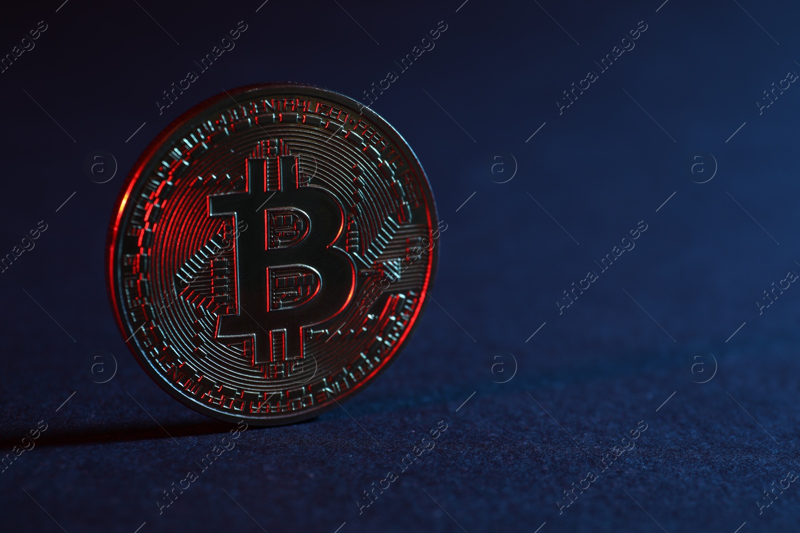 Photo of Bitcoin on blue background in red light, closeup with space for text