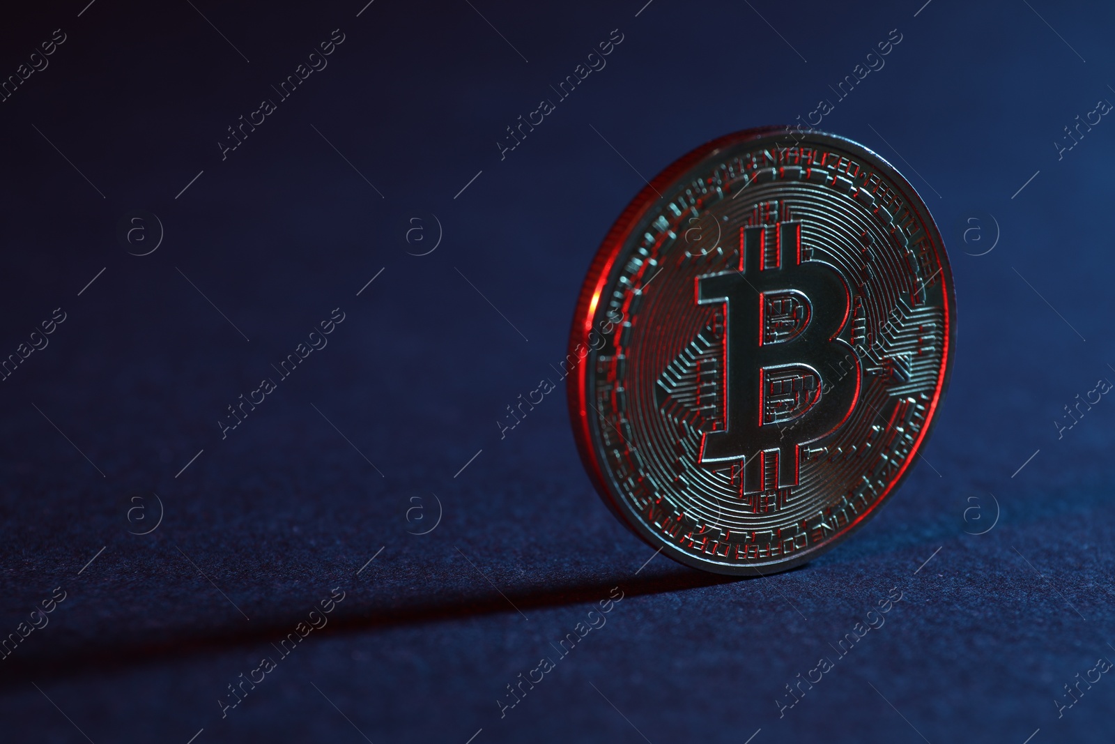 Photo of Bitcoin on blue background in red light, closeup with space for text