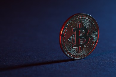 Photo of Bitcoin on blue background in red light, closeup with space for text