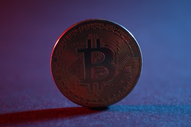 Photo of Bitcoin on blue background in red light, closeup