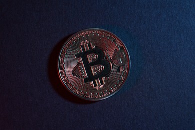 Photo of Bitcoin on blue background in red light, top view