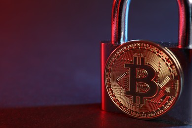 Photo of Bitcoin and padlock on blue background in red light, closeup with space for text