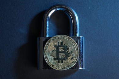 Photo of Bitcoin and padlock on blue background, top view