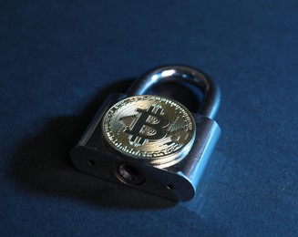 Photo of Bitcoin and padlock on blue background, closeup