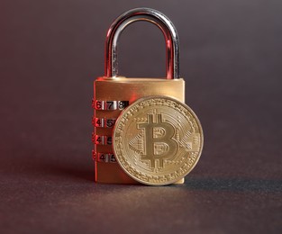Photo of Bitcoin and padlock on grey background in red light, closeup