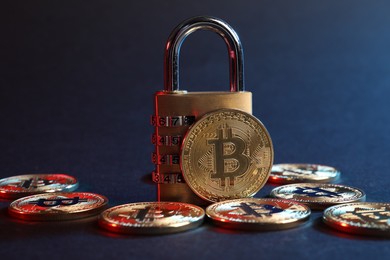 Photo of Bitcoins and padlock on blue background in red light, closeup