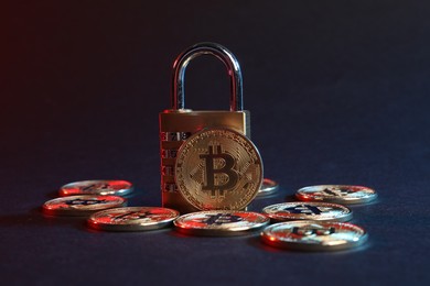 Photo of Bitcoins and padlock on blue background in red light, closeup