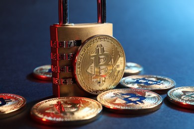 Photo of Bitcoins and padlock on blue background in red light, closeup