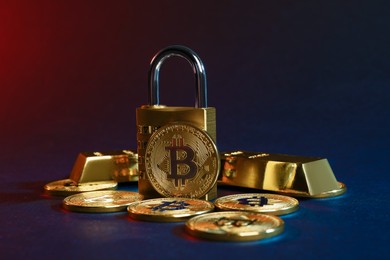 Photo of Bitcoins, padlock and gold bars on blue background, closeup
