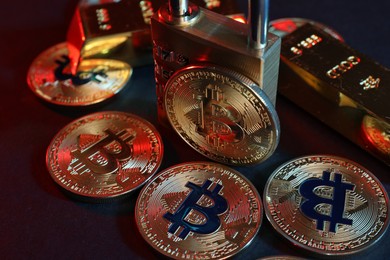 Photo of Bitcoins, padlock and gold bars on blue background, closeup