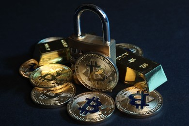 Photo of Bitcoins, padlock and gold bars on blue background, closeup