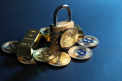 Photo of Bitcoins, padlock and gold bars on blue background, closeup