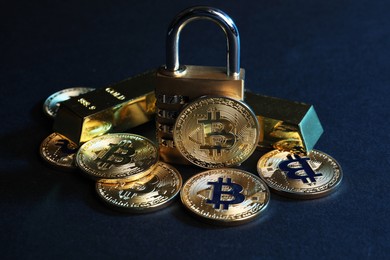 Photo of Bitcoins, padlock and gold bars on blue background, closeup