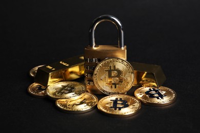 Photo of Bitcoins, padlock and gold bars on black background, closeup