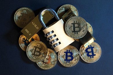 Photo of Bitcoins, padlock and gold bars on blue background, top view