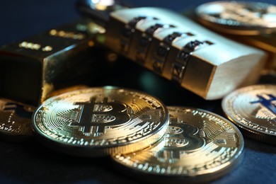 Photo of Bitcoins, padlock and gold bar on dark background, closeup