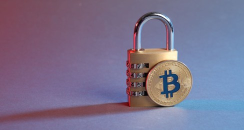Photo of Bitcoin and padlock on color background, closeup. Space for text