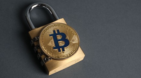Photo of Bitcoin and padlock on grey background, closeup. Space for text