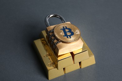 Photo of Bitcoin, padlock and gold bars on grey background, closeup