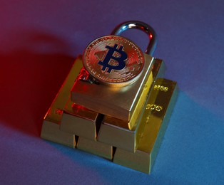 Photo of Bitcoin, padlock and gold bars on color background in red light, closeup