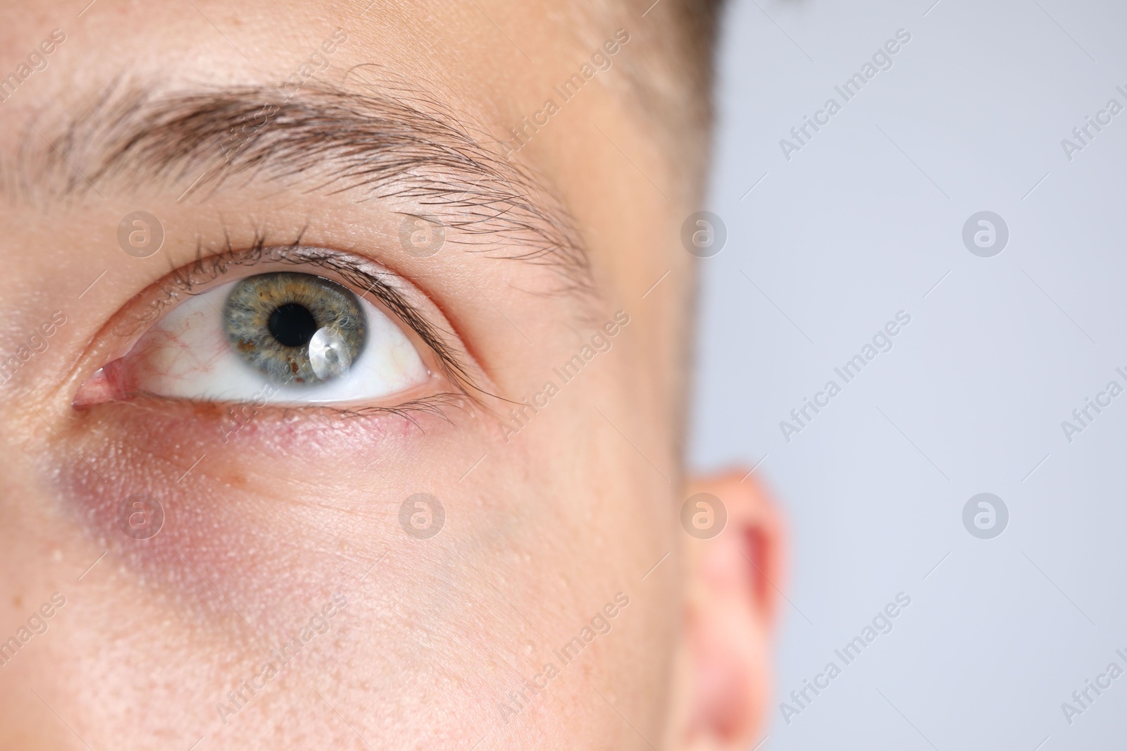 Photo of Man with beautiful eyes on light grey background, closeup. Space for text