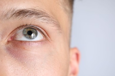 Photo of Man with beautiful eyes on light grey background, closeup. Space for text