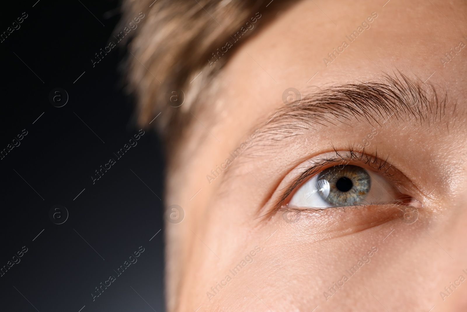 Photo of Man with beautiful eyes on black background, closeup