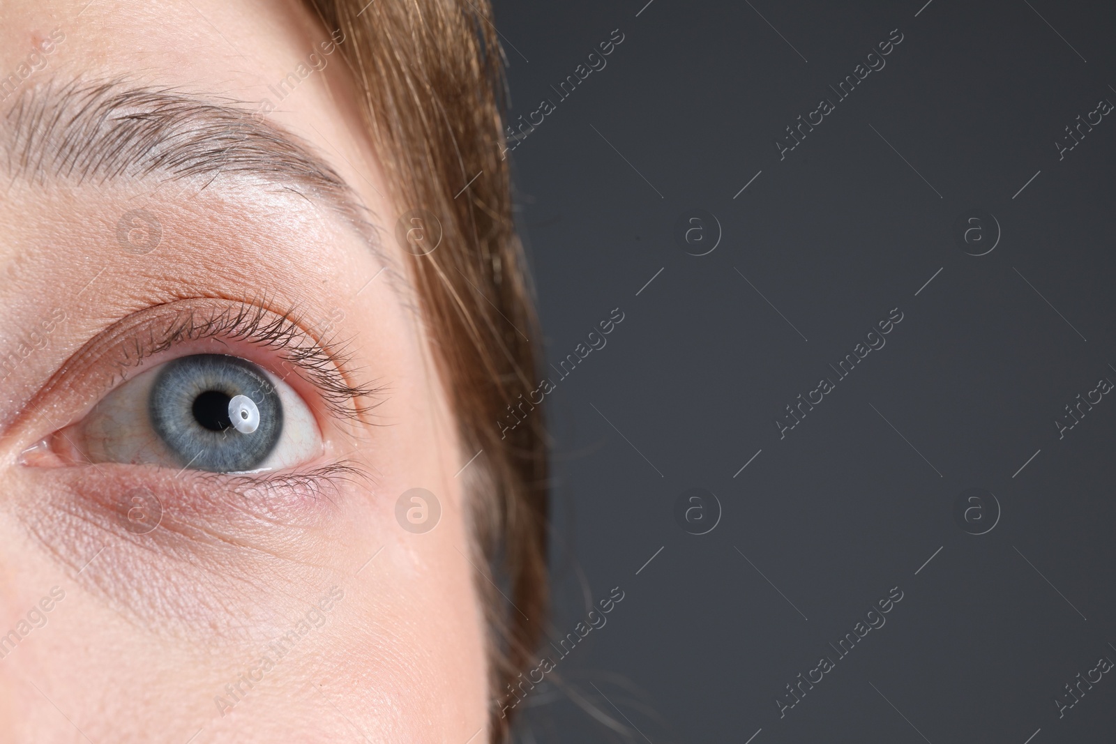 Woman with beautiful eyes on grey background, closeup. Space for text Photo of Woman with beautiful eyes on grey background, closeup. Space for text