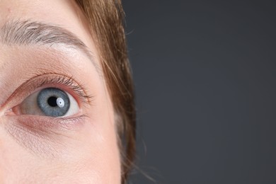 Photo of Woman with beautiful eyes on grey background, closeup. Space for text