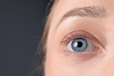 Photo of Woman with beautiful eyes on grey background, closeup. Space for text