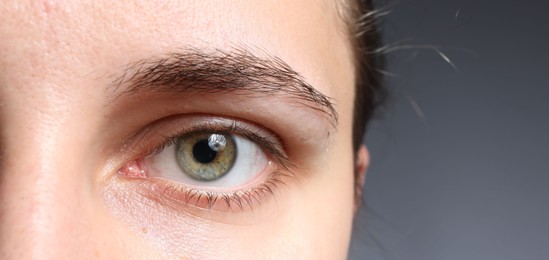 Photo of Woman with beautiful eyes on grey background, closeup. Space for text