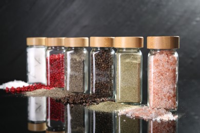Photo of Different spices and glass jars on mirror surface, closeup
