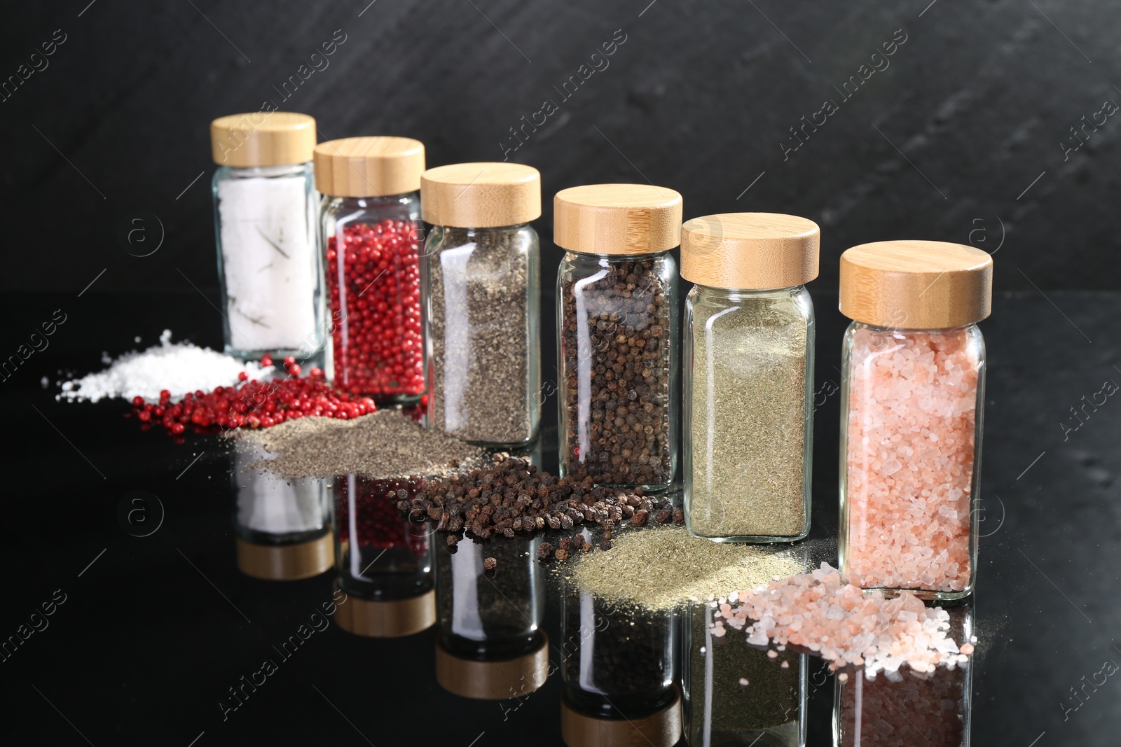 Photo of Different spices and glass jars on mirror surface