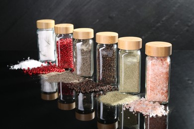 Photo of Different spices and glass jars on mirror surface
