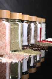 Photo of Different spices and glass jars on mirror surface, closeup